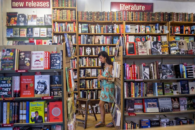 Aisha Guthrie passes by shelves of books of the independent bookstore, A Cappella, that has been an Atlanta staple for decades. JONATHAN PHILLIPS / SPECIAL (The Atlanta Journal-Constitution)