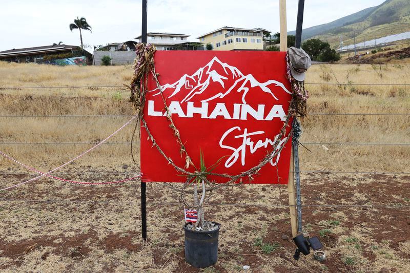 A sign is seen at a roadside memorial dedicated to the Maui wildfires, Friday, April 12, 2024, in Lahaina, Hawaii. More than half a year after the deadliest U.S. wildfire in more than a century burned through a historic Maui town, officials are still trying to determine exactly what went wrong and how to prevent similar catastrophes in the future. But two reports released this week are filling in some of the blanks. (AP Photo/Marco Garcia)