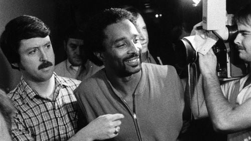 Then-Sgt. Mike Sellers (left) escorts Carlton Gary (center) — aka the “Stocking Strangler” — through a crowd of reporters and photographers in the hours after Columbus, Ga., police arrested Gary in 1984. (Photo credit: Special / Columbus Ledger-Enquirer)