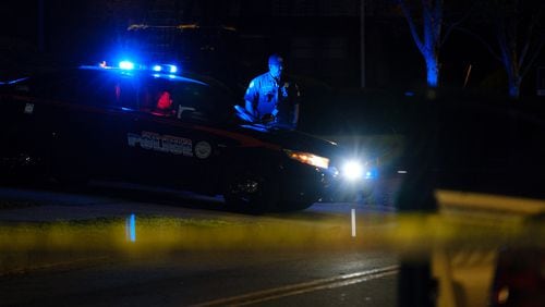 Police are seen at a scene where a man was found shot and dead inside a sedan after it crashed into a fence at a southwest Atlanta apartment complex on Friday, April 15, 2022. The crash occurred outside of the Donnelly Courts apartments.  (Arvin Temkar / arvin.temkar@ajc.com)