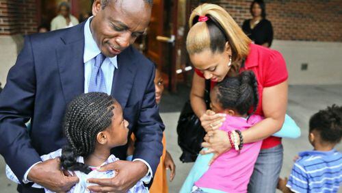 DeKalb County Schools Superintendent, Michael Thurmond (left) and Ronald E. McNair Discovery Learning Academy technology teacher, Shanique Worthey (right) hug elementary children as they arrive for classes at McNair high school.
