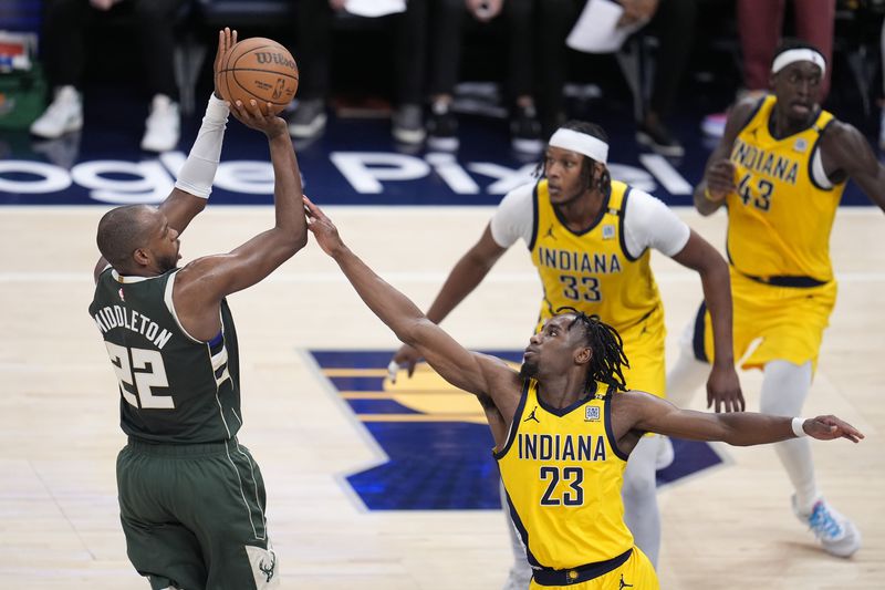Milwaukee Bucks' Khris Middleton (22) shoots over Indiana Pacers' Aaron Nesmith (23) during the first half of Game 4 of the first round NBA playoff basketball series, Sunday, April 28, 2024, in Indianapolis. (AP Photo/Michael Conroy)