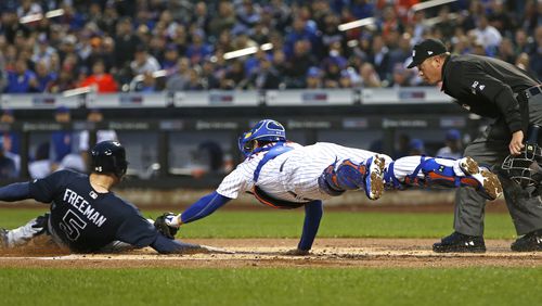 New York Mets catcher Travis d’Arnaud tries to tag the Braves’ Freddie Freeman during the first inning. Home plate umpire Cory Blaser is at right. Freeman was originally called out, but was ruled safe after a challenge by the Braves. (AP Photo/Kathy Willens)