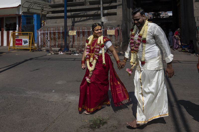Newly wed Dileep Kumar, right, walks with his bride Narayani outside in the southern Indian city of Chennai, April 15, 2024. Kumar, a computer engineer in Bengaluru, said voters in Tamil Nadu are wary that the ruling party of Prime Minister Narendra Modi wants to impose Hindi language on the state. (AP Photo/Altaf Qadri)