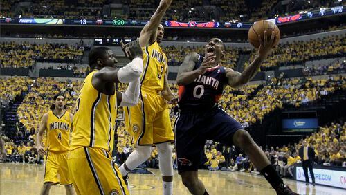 Atlanta Hawks' Jeff Teague shoots against Indiana Pacers' Roy Hibbert and George Hill (3) during the first half in Game 1 of an opening-round NBA basketball playoff series on Saturday, April 19, 2014, in Indianapolis. (AP Photo/Darron Cummings)