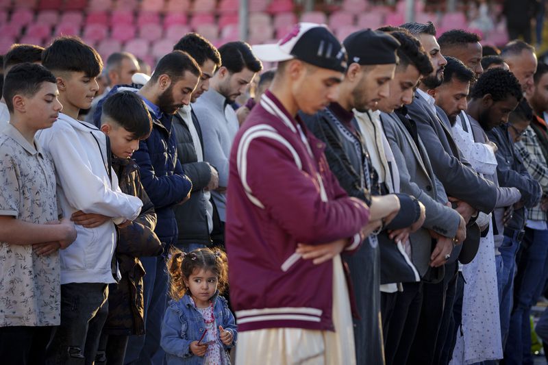 A little girl takes part alongside men in Eid al-Fitr prayers in Bucharest, Romania, Wednesday, April 10, 2024. Members of the Romanian Muslim community joined prayers at the Dinamo stadium in the Romanian capital, in the largest Muslim public gathering of the year. Eid al-Fitr marks the end of the holy fasting month of Ramadan. (AP Photo/Andreea Alexandru)