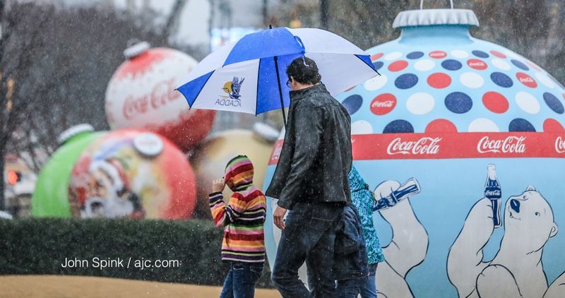 The Roulo family of Savannah braves heavy rain outside the World of Coca-Cola on Wednesday. JOHN SPINK / JSPINK@AJC.COM
