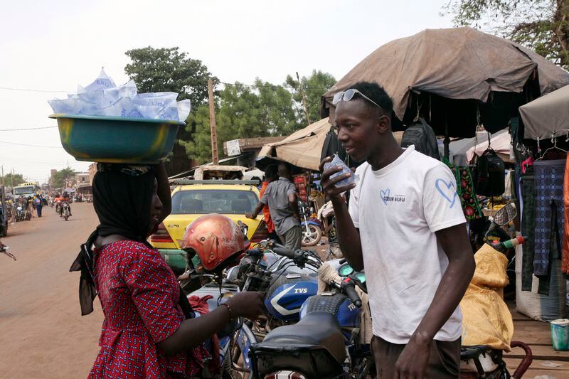 Amadou Coulibaly, a 25-years-old, motorcycle taxi driver, drinks a sachet water to cool off under a blazing sun.in Bamako, Mali, Thursday, April, 18, 2024. Street vendors in Mali's capital of Bamako peddle water sachets, ubiquitous for this part of West Africa during the hottest months of the year. On Thursday, temperatures in Bamako reached 44 degrees Celsius (111 Fahrenheit) and weather forecasts say it's not letting up anytime soon. (AP Photo/Baba Ahmed)