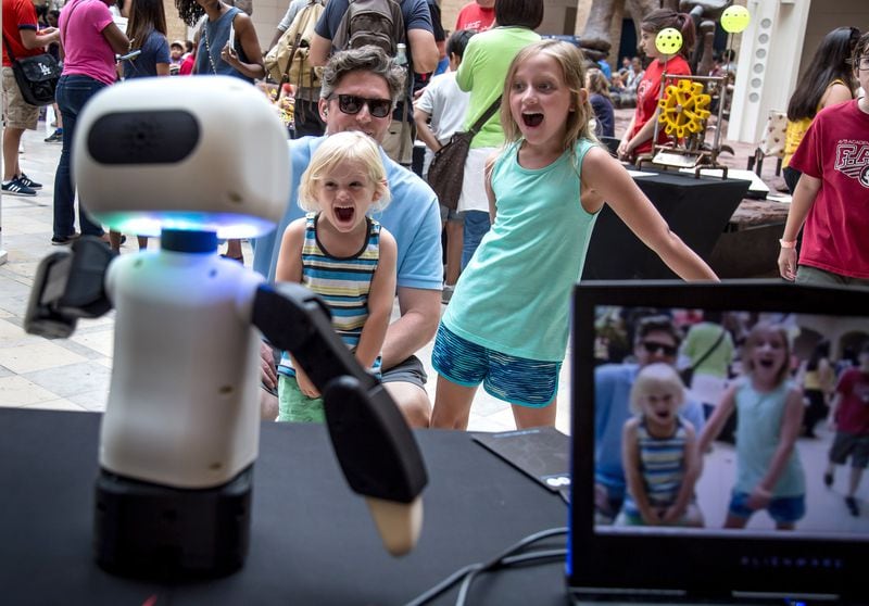 Kyle Hunt and his two daughters Ras (center) and Emersyn try to get a robot’s attention during Robots Day at the Fernbank Museum of Natural History on Saturday, June 23, 2018. (STEVE SCHAEFER / SPECIAL TO THE AJC)