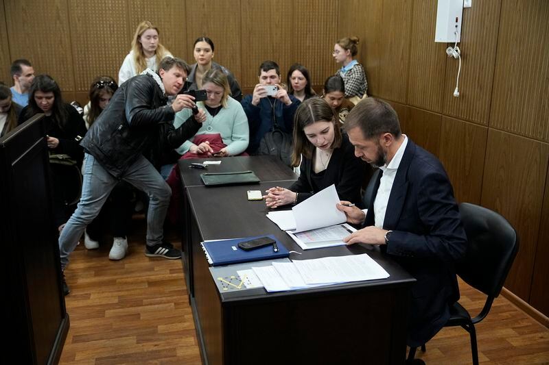 Lawyers of TV presenter and actress Anastasia Ivleeva, right, work on documents as they and supporters wait for the court session at the Zamoskvoretsky district court Thursday, April 25, 2024. A Moscow court on Thursday imposed a 50,000-ruble ($560) fine for discrediting the military on Anastasia Ivleeva, a TV presenter and actress whose party for scantily clad guests sparked an explosion of public indignation in the increasingly traditionalist country. (AP Photo/Alexander Zemlianichenko)