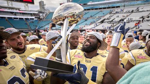 Georgia Tech defensive lineman Patrick Gamble (91) and his teammates celebrate with the trophy after the TaxSlayer Bowl NCAA college football game against Kentucky, Saturday, Dec. 31, 2016, in Jacksonville, Fla. Georgia Tech beat Kentucky 33-18. (AP Photo/Stephen B. Morton)