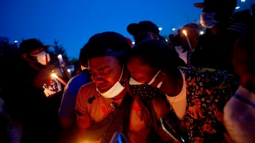 Maalik Mitchell, center left, sheds tears as he says goodbye to his father, Calvin Munerlyn, during a vigil Sunday in Flint, Michigan.  Munerlyn was shot and killed Friday at a Family Dollar store in Flint. He'd worked at the store as a security guard for a little more than a year.