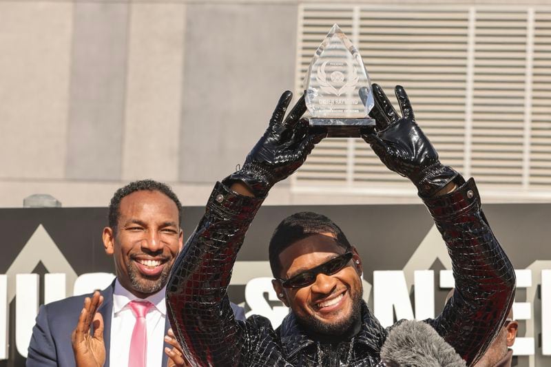 Usher holds up the Phoenix Award presented by Mayor Andre Dickens at The Black Music Walk of Fame in Atlanta on Feb. 14. Photo by Natrice Miller/ Natrice.miller@ajc.com