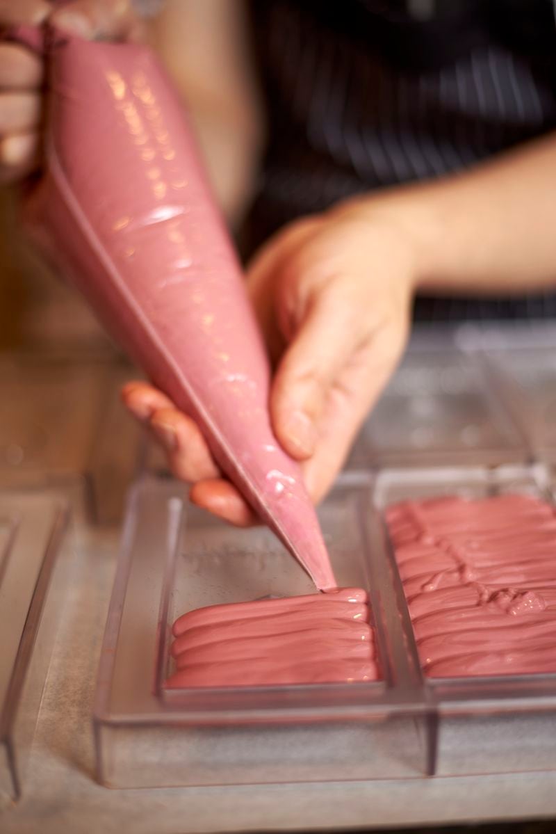 To make these chocolate bars, Thomas Numprasong uses a piping bag to fill molds with ruby chocolate. Courtesy of Kyle Reynolds