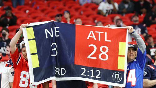 111821 Atlanta: Patriots fans hold a sign reminding Falcons fans of their blown Super Bowl loss to the Patriots during their current 25-0 shut out in Mercedes-Benz Stadium sporting many empty seats in a NFL football game on Thursday, Nov. 18, 2021, in Atlanta.    “Curtis Compton / Curtis.Compton@ajc.com”