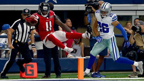 Julio Jones leaps over the goal line to score a touchdown as Tyler Patmon of the Dallas Cowboys looks on the in the third quarter at AT&T Stadium on September 27, 2015 in Arlington, Texas.