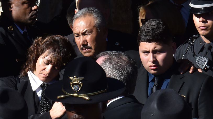 December 18, 2018 Dunwoody - Family members of officer Edgar Isidro Flores react as the casket of officer Edgar Isidro Flores is brought out at All Saints Catholic Church in Dunwoody on Tuesday, December 18, 2018. Flores was shot and killed in DeKalb County in the line of duty last week. HYOSUB SHIN / HSHIN@AJC.COM