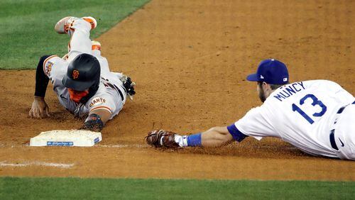 The San Francisco Giants' Chadwick Tromp slides back to first base as Los Angeles Dodgers first baseman Max Muncy (13) tries to catch him off the bag during the seventh inning at Dodger Stadium in Los Angeles on Friday, Aug. 7, 2020. The Dodgers won, 7-2. (Katelyn Mulcahy/Getty Images/TNS)