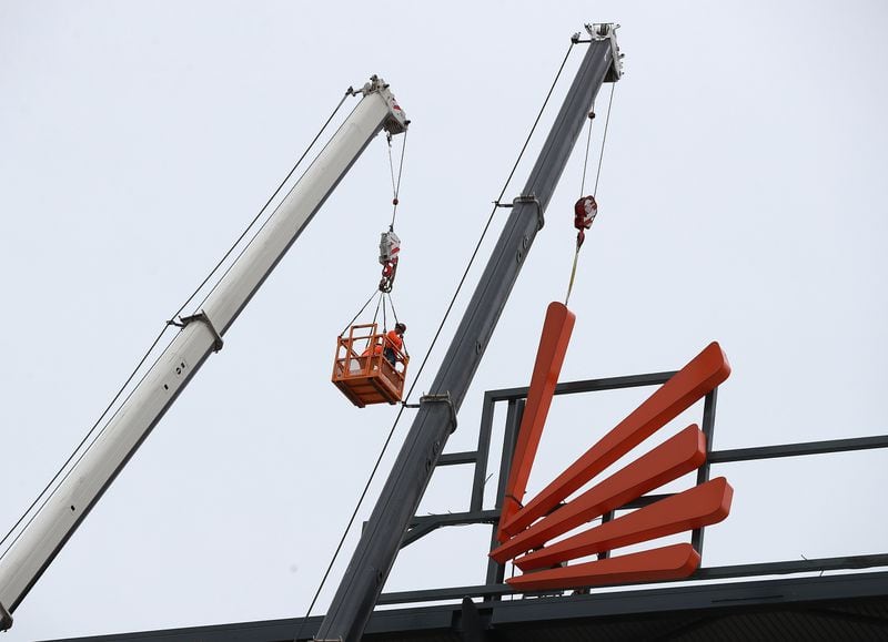 Workers with Georgia Rigging Inc. use two large cranes Tuesday to remove the final pieces of a SunTrust Park sign at newly renamed Truist Park.