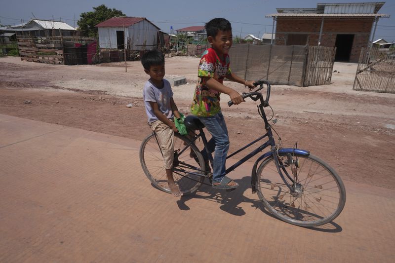Boys, who are among the families relocated from Cambodia's archaeological site, ride bicycle at Run Ta Ek village in Siem Reap province, Cambodia, on April 2, 2024. Cambodia's program to relocate people living on the famous Angkor archaeological site is drawing international concern over possible human rights abuses, while authorities maintain they're doing nothing more than protecting the UNESCO World Heritage Site from illegal squatters. (AP Photo/Heng Sinith)
