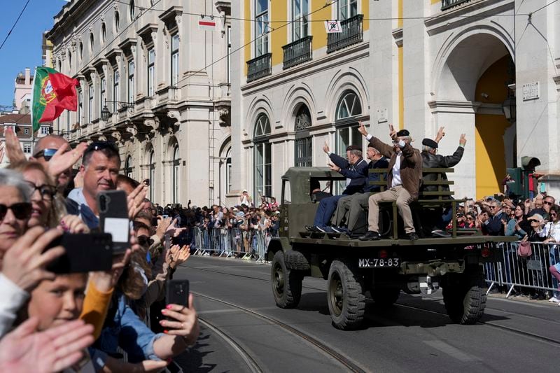 People cheer at the sight of a military truck that took part in the 1974 Carnation revolution, at Lisbon's Comercio square, Thursday, April 25, 2024, during celebrations of the fiftieth anniversary of the military coup. The April 25, 1974 revolution carried out by the army restored democracy in Portugal after 48 years of a fascist dictatorship. (AP Photo/Ana Brigida)