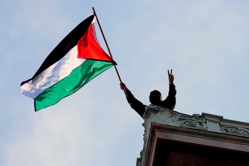 FILE - A student protester waves a Palestinian flag above Hamilton Hall on the campus of Columbia University, Tuesday, April 30, 2024, in New York. (Pool Photo/Mary Altaffer, File)