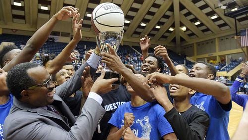 Westlake head coach Darron Rogers (left) and the Westlake Lions hold the trophy and game ball after winning the Class AAAAAA boys championship last season.