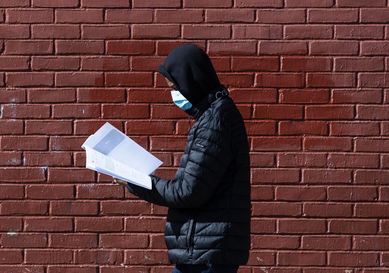 Terrell Bell, wearing a protective facemask, looks at a learning guide he picked up for his sister at John H. Webster Elementary School in Philadelphia. 