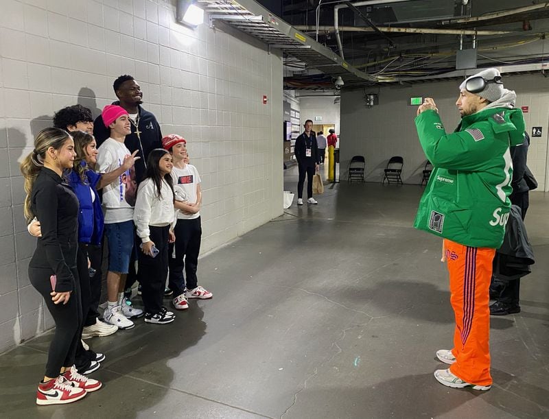 New Orleans Pelicans guard Jose Alvarado (green jacket) takes a photo of teammate Zion Williamson (black warmup suit) with young members of a party of friends and relatives of Alvarado's who had come to support the former Georgia Tech star at the Hawks-Pelicans game at State Farm Arena March 10, 2024. The children had asked Alvarado to set up a photo with the NBA star, a request he obliged. (AJC photo by Ken Sugiura)