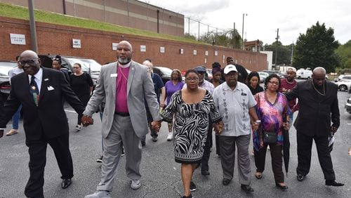 Tamara Cotman, center,  holds hands with supporters as she walks to the Fulton County Jail Tuesday. Cotman, convicted in the Atlanta Public Schools cheating scandal, will begin serving her prison sentence after her appeals ran out.
