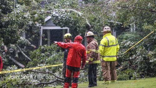 Outside of where a tree crashed into a home and killed a Sandy Springs man, authorities discuss how to get inside the home on Monday, Sept. 11, 2017. (JOHN SPINK/AJC)