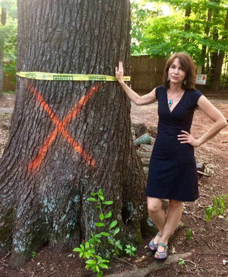 Stephanie Stuckey, who filed an appeal to save more trees along DeKalb Avenue, stands by a doomed red oak that was likely alive during the Civil War.