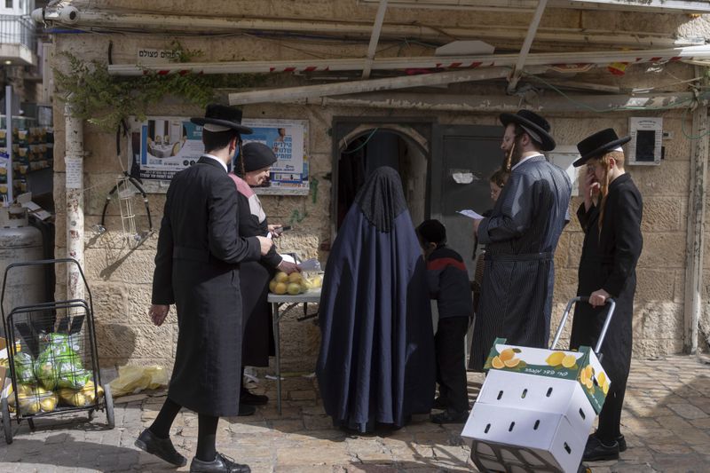 Ultra-Orthodox Jews collect food distributed to large families for free, in a special market ahead of the upcoming Passover holiday in Jerusalem, Thursday, April 18, 2024. Jews are forbidden to eat leavened foodstuffs during the Passover holiday that celebrates the biblical story of the Israelites' escape from slavery and exodus from Egypt. (AP Photo/Ohad Zwigenberg)