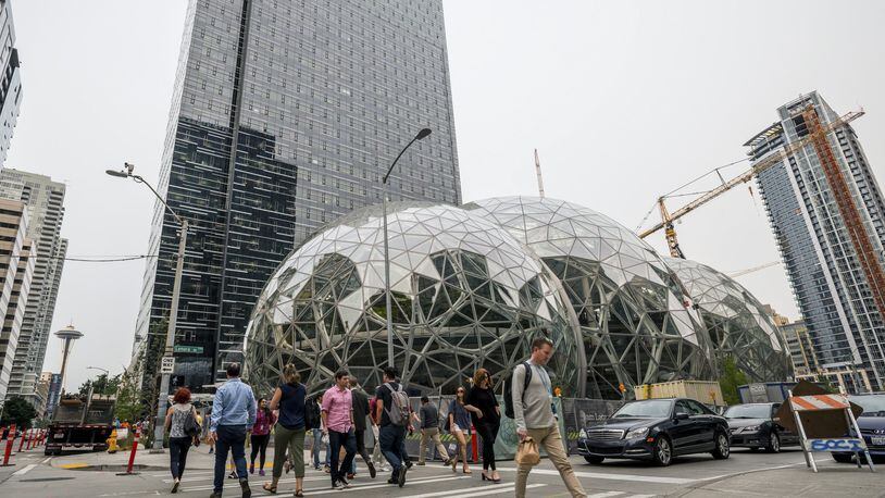Pedestrians walk past a recently built trio of geodesic domes that are part of the Seattle headquarters for Amazon. The online retail giant said it was searching for a second headquarters in North America in 2017, a huge new development that would cost as much as $5 billion to build and run, and house as many as 50,000 employees. (Stuart Isett/The New York Times)