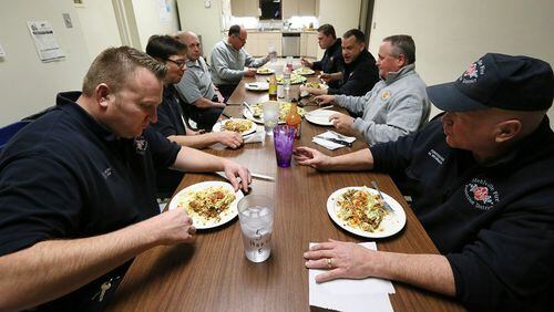 Firefighters from Engine House No. 5 sit together for a Taco Pizza dinner made with fire/medic Jake Lickteig's (foreground left) recipe on Thursday, Jan. 21, 2016, at the Mehlville Fire Protection District Engine House No. 5 in St. Louis, Mo. The two pizzas fed seven firefighters with about half of a pizza left over. (Chris Lee/St. Louis Post-Dispatch/TNS)