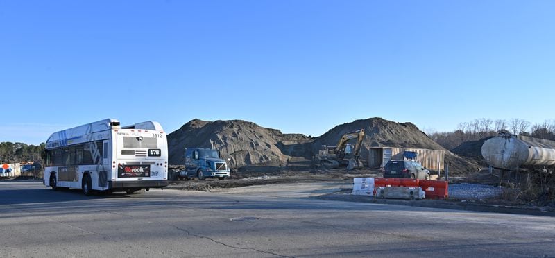 Un bus MARTA passe devant des tas de déchets sur un site géré par TAV Holdings Inc.  le mercredi 26 janvier 2022. L'EPA continue de sonder la contamination hors site à partir du site, et une enquête distincte de l'OSHA sur les conditions de travail dans l'installation est en cours. 