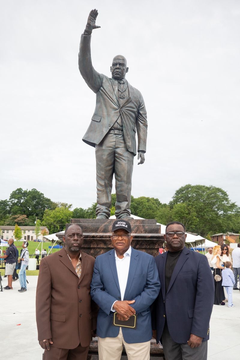 Adolf, Samuel, and Henry Lewis stand by the statue of the late Congressman John Lewis at Rodney Cook Sr. Park in Vine City in Atlanta, GA., on Wednesday, June 7, 2021. (Photo/ Jenn Finch for The Atlanta Journal-Constitution)