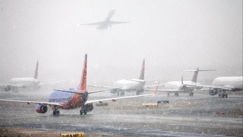 Planes line up on the tarmac as snow falls delaying travel at Hartsfield-Jackson Atlanta International Airport Friday, Dec. 8, 2017, in Atlanta.