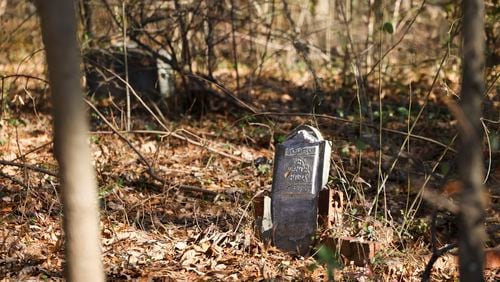 Gravestones in the Piney Grove Cemetery next to the Bluffs at Lenox townhome development in Buckhead are overgrown with vegetation. The complex's homeowners association is being sued for alleged negligence by descendants of those buried in the cemetery. (Jason Getz / Jason.Getz@ajc.com)