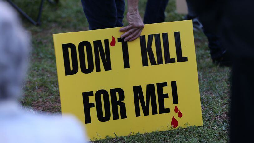 A death penalty opponent holds a sign outside the Georgia Diagnostic and Classification State Prison in Butts County during a protest in March 2016. The state's execution chamber is located at the prison.