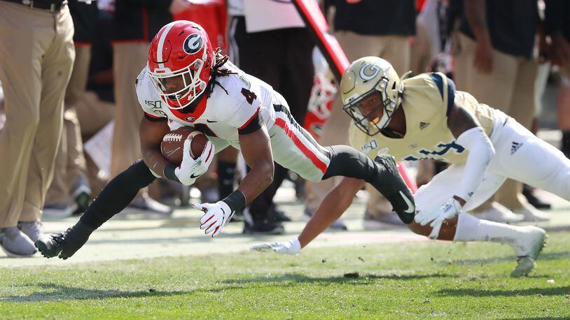 November 30, 2019 Atlanta: Georgia tailback James Cook stretches for extra yardage past Georgia Tech defender Jaylon King during the first half in a NCAA college football game on Saturday, November 30, 2019, in Atlanta.  Curtis Compton/ccompton@ajc.com