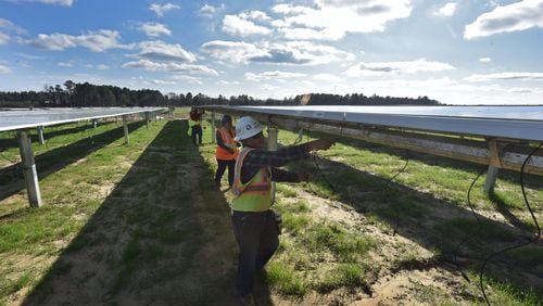 Workers with Solar Panel Solutions install solar panels in February in Bronwood, Ga., in the southern part of the state. HYOSUB SHIN / HSHIN@AJC.COM