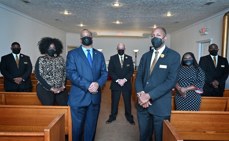 Dudley Funeral Home has been operating in Dublin for a century. In August and September of 2020, it was handling two or three services a day, said Carl Pearson (foreground right), director of client services. The funeral home usually does five or six funerals a week. Managing Director Alfred Pearson Jr. (foreground left) poses with the funeral home staff. (Hyosub Shin / Hyosub.Shin@ajc.com)