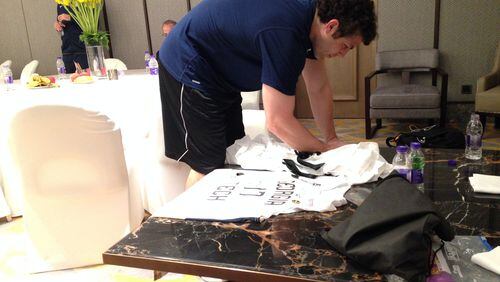Georgia Tech coach Josh Pastner autographs a jersey to be presented as a gift during the team's stay in China. The Yellow Jackets will play UCLA Saturday (Friday night in the U.S.) in Shanghai. (AJC photo by Ken Sugiura)