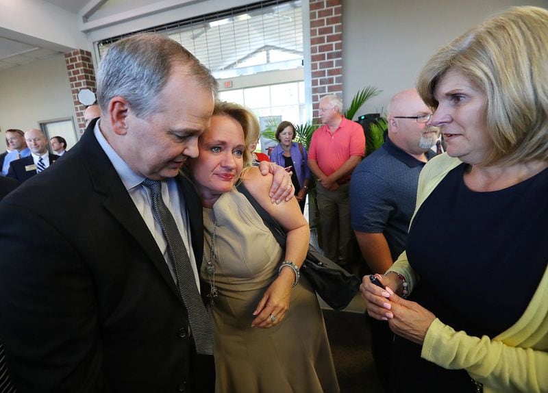 Emotion filled the room as Kathy (right) and Craig Clark (left), who lost their daughter Emily Clark, embrace Cheri Madliak (center), who also lost her child to a distracted driver, after Governor Nathan Deal signed HB 673 prohibiting Georgia motorists from handling their cell phones while driving during a ceremony at the Statesboro-Bullock County Airport on Tuesday in Statesboro. HB 673 is the most sweeping change in driving rules since lawmakers banned texting while driving. The families of five nursing students who died when they were struck by a semi on nearby I-16, including the Clarks, attended the ceremony. Curtis Compton/ccompton@ajc.com