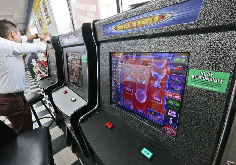 A technician opens a coin-operated amusement machine at a Duluth gas station in July. Nearly 6,000 Georgia gas stations, convenience stores, Laundromats and American Legion posts - as well as ventures like Hariz USA, Lucky Latin Games and Nickle Pumper - now have what the state calls coin-operated amusement machines and lawmakers described as games of skill. As of July 1st, the machines are monitored by the state Lottery Corporation. BOB ANDRES / BANDRES@AJC.COM