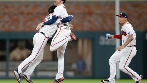 Atlanta Braves' Dansby Swanson, left, celebrates with Freddie Freeman as Jace Peterson rushes in after hitting a game-winning base hit in the ninth inning of a baseball game against the San Diego Padres, Monday, April 17, 2017, in Atlanta. Atlanta won 5-4. (AP Photo/John Bazemore)