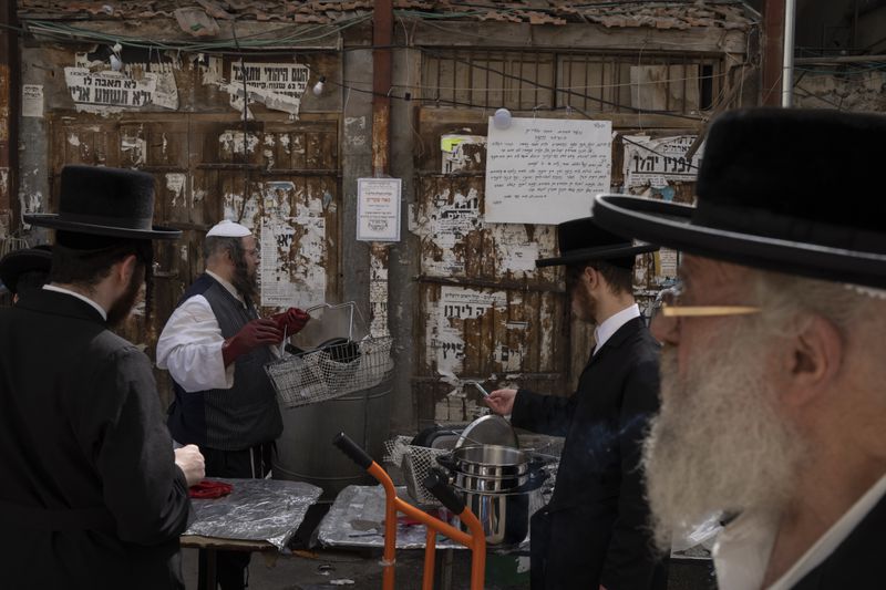 An ultra-Orthodox Jewish man dips cooking utensils in boiling water to remove remains of leaven in preparation for the upcoming Jewish holiday of Passover in the ultra-Orthodox neighbourhood Mea Shearim, in Jerusalem, Thursday, April 18, 2024. Jews are forbidden to eat leavened foodstuffs during the Passover holiday that celebrates the biblical story of the Israelites' escape from slavery and exodus from Egypt. (AP Photo/Leo Correa)