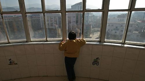 An autistic child looks out a window.