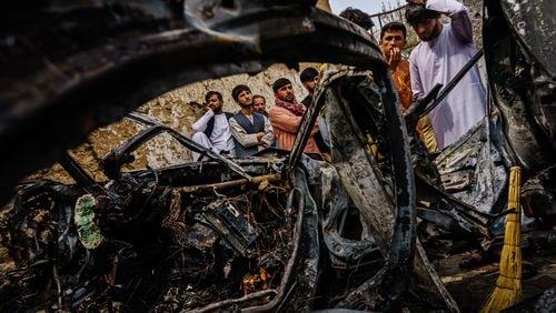 Relatives and neighbors of the Ahmadi family gathered around the incinerated husk of a vehicle that the family says was hit by a U.S. drone strike, in Kabul, Afghanistan on Aug. 30.